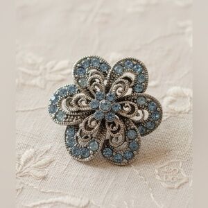 Vintage silver filigree floral brooch with light blue rhinestones